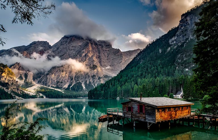 Satan's Biggest Trick: Peaceful mountain lake scene featuring a rustic boathouse and stunning reflections.